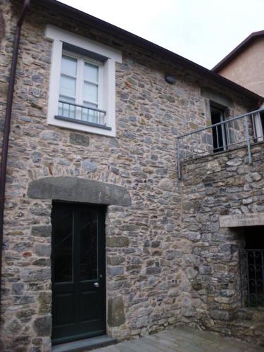 a stone building with a black door and a window at Casa Natale in Corvara