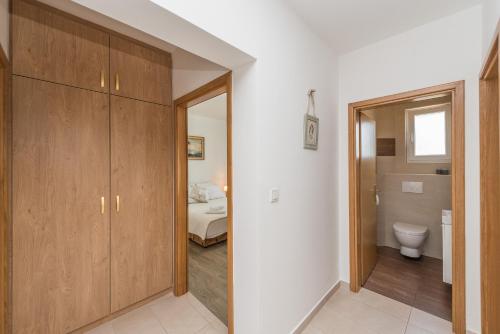 a bathroom with wooden cabinets and a toilet in a room at Apartment Miriam with grill and terrace - by TA Leut Agency in Privlaka