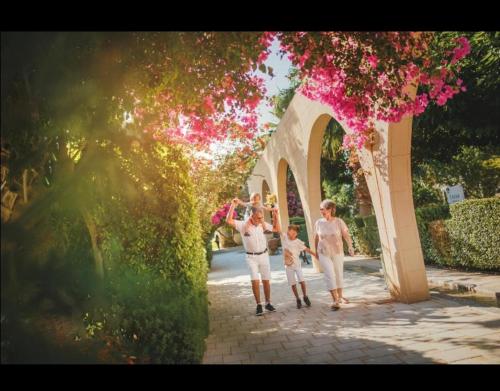 a family walking under an arch with pink flowers at Caesar Resort studio in Iskele