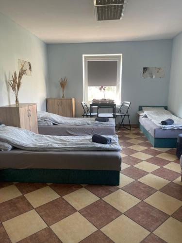 1 dormitorio con 3 camas y suelo a cuadros en Wiejska Chata w Doline Baryczy, en Ujeździec Mały