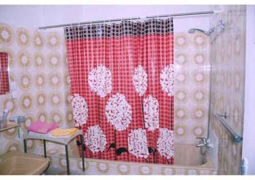 a bathroom with a shower with a red and white shower curtain at Appartement Spacieux pour Famille Mâarif Casablanca in Maarif