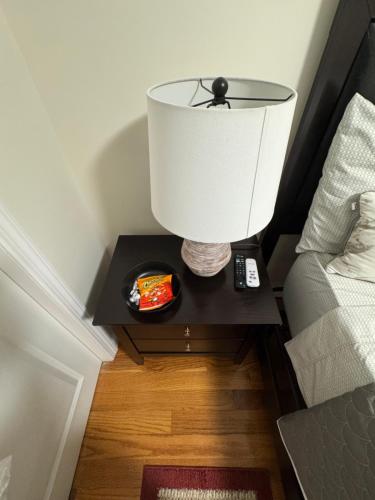 a lamp on a night stand next to a bed at Guiding Light in Springfield Gardens
