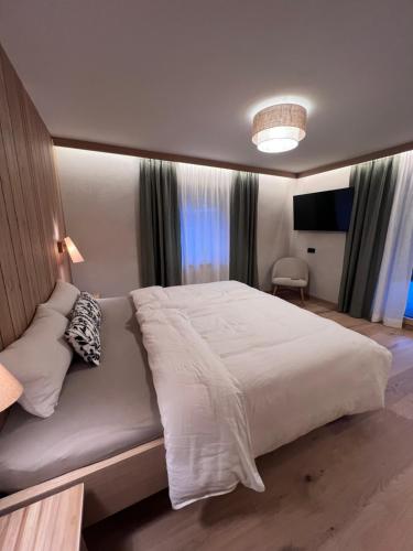 a bedroom with a large white bed and a television at Apart Bieles NEU - Bergoase mit privater Outdoor-Sauna & Massagepraxis in Kauns