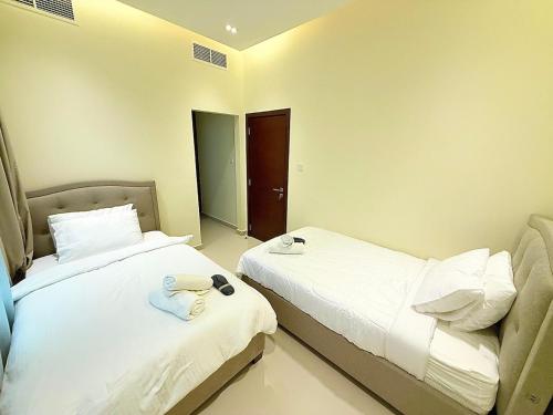 two beds in a hotel room with white sheets at Lux 3BR Villa, Sea Views & Pool in Sharm