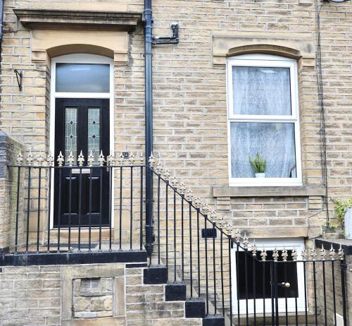 a brick house with a black door and two windows at Cosy 3 Bed Home, Holywell Green in Greetland