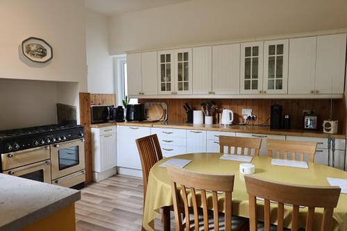 a kitchen with a table and chairs and a kitchen with white cabinets at Cosy 3 Bed Home, Holywell Green in Greetland