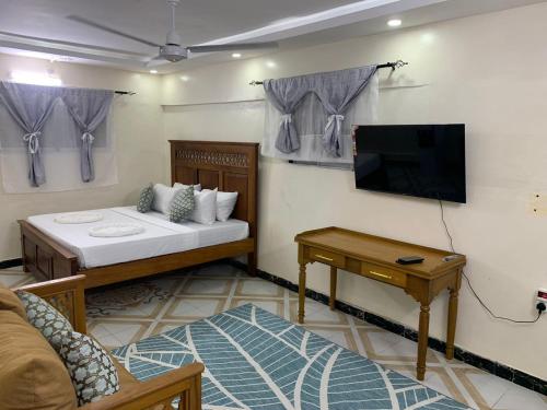a room with a bed and a tv and a couch at Fatnaish Rooftop Apartment in Lamu