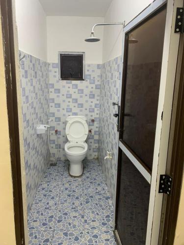 a bathroom with a toilet with blue tiles at Fatnaish Rooftop Apartment in Lamu