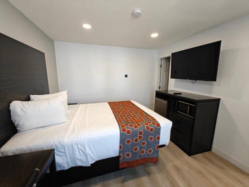 a hotel room with a bed and a flat screen tv at Casa Blanca Inn and Suites in Chandler