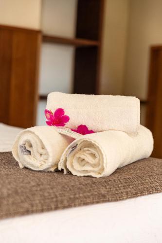 a stack of towels with flowers on a bed at Pousada Paraíso Açú in Itaipava