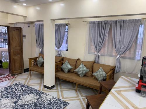 a living room with a couch and some windows at Fatnaish Riyadha Apartment in Lamu