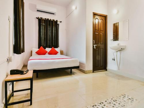 a bedroom with a bed with red pillows and a sink at Super Hotel O Capital Pearl in Patna