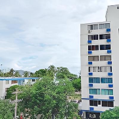 a tall white building with blue windows on it at Apartaestudio cerca al mar - Disfruta santa marta in Gaira