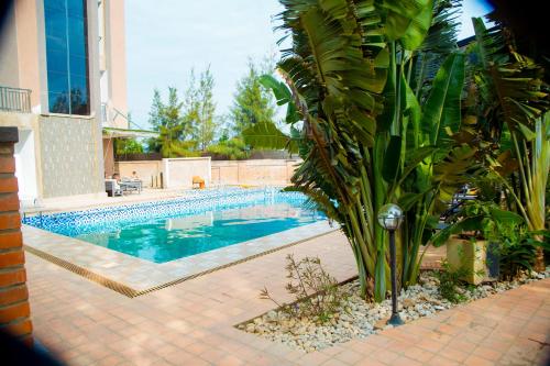 a swimming pool with a palm tree next to a house at Novaland Hotel in Kigali