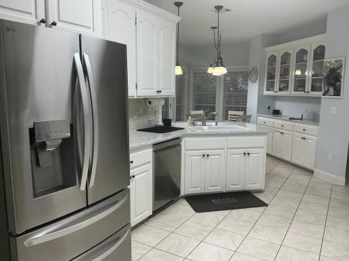 a kitchen with a stainless steel refrigerator and white cabinets at Spacious King Suite Home With Serene Patio in Hattiesburg