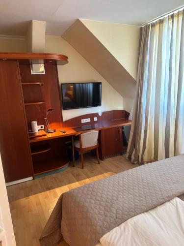 a bedroom with a bed and a desk with a television at Berliner Hof in Dallgow