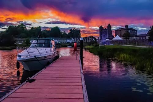 a boat is docked at a dock with a sunset at TJ’s Cottage in Enniskillen