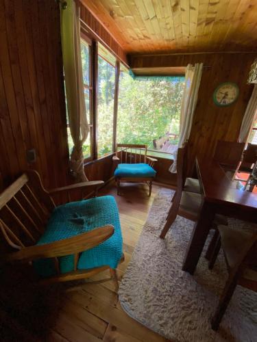 a living room with a couch and a table and windows at Exquisita Cabaña familiar a minutos del Lago Caburgua y Pucón in Caburgua