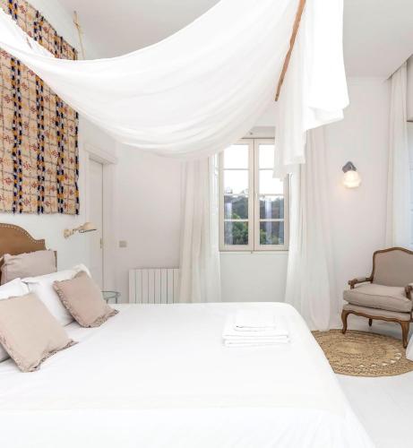 a white bedroom with a bed and a chair at Quinta de Sá in Vila Nova de Gaia