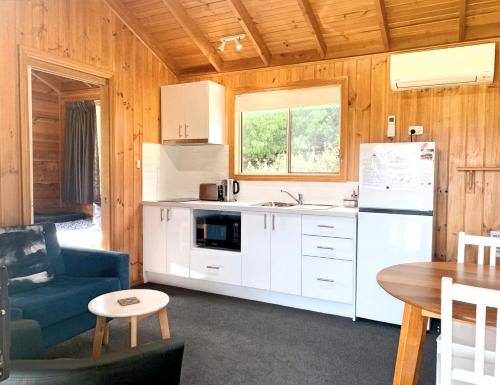 a kitchen with white cabinets and a blue couch and a table at Maydena Mountain Cabins in Maydena