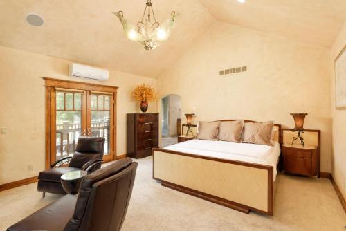 a bedroom with a bed and a chair and a chandelier at Luxe Artful Mountain Retreat with 4 King Suites, 8 Person Hot Tub and 3 Decks in Carbondale