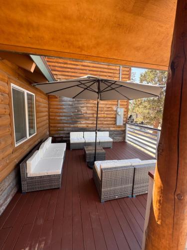 an outdoor patio with an umbrella and chairs and tables at Bear House in Big Bear City