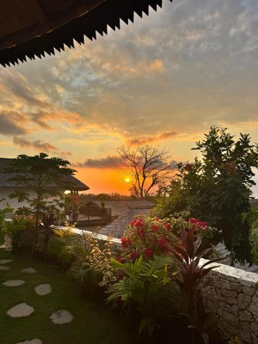 a sunset over a garden with flowers and trees at Penida View Village - Infinity pool & Volcano View in Nusa Penida