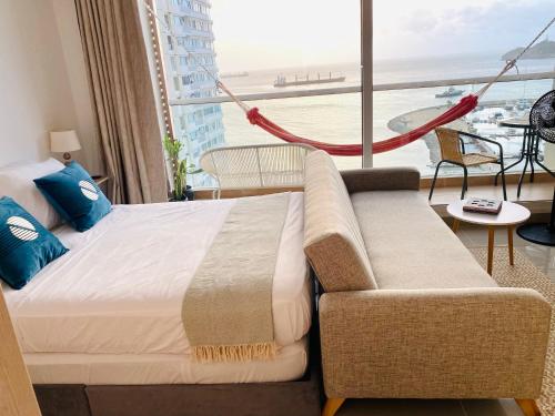 a bedroom with a bed and a couch and a large window at "Blue loft Oceanview Minimalist Studio in Marina Rooftop Pool Prime Location" in Santa Marta