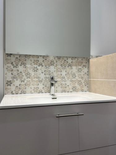 a bathroom with a white sink and a tile wall at Argence logement T2 in Angoulême