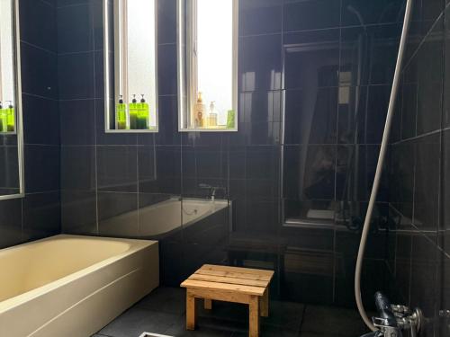 a bathroom with a bath tub and a table at My Chalet Hakuba in Hakuba