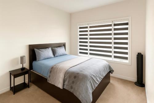 a white bedroom with a bed and a window at 2024 Built Elegant 3BR Kleinburg Vaughan Townhouse with Free Parking, WiFi, Full Kitchen, Laundry, Near Canada's Wonderland! Perfect for Family Travel, Group Trips or Work Stays! in Vaughan