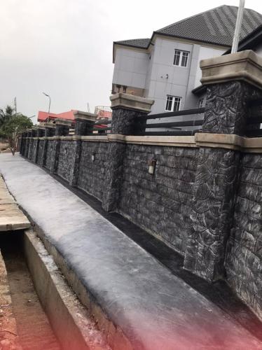 a stone wall with snow on it in front of a house at International royal hotel in Owerri