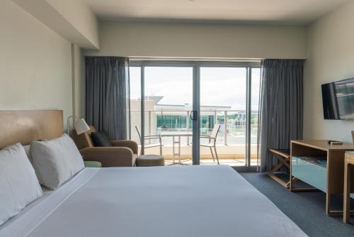Stuart ParkにあるDarwin Harbour and City Views Apartmentsの大きなベッドとバルコニーがあるホテルの部屋