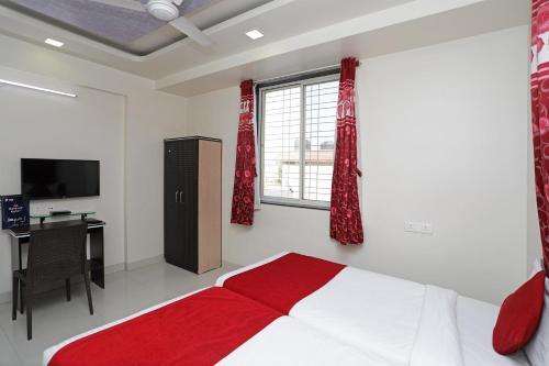 a bedroom with a bed and a desk and a window at Hotel O Galaxy Apartments Near Pune Airport in Pune