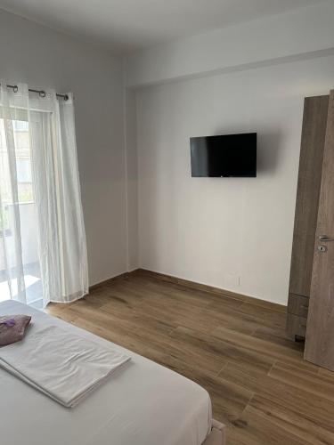 a white room with a bed and a flat screen tv at La casa de Alex in Sarandë