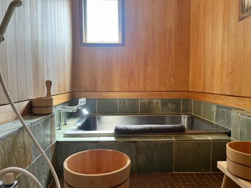 a large bath tub in a room with a window at Corduroy Ski Lodge Madarao Tangram in Shinano