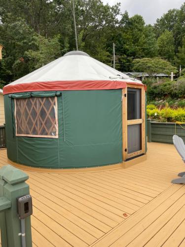 a green tent on a deck with a chair at Mountain Aire Cottages, Inn, & Glamping in Clayton