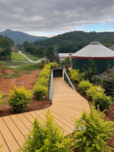 a wooden walkway leading to a yurt with a tent at Mountain Aire Cottages, Inn, & Glamping in Clayton