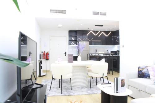 a living room with a table and white chairs at Dubai Marina 1BR with Balcony, Near Metro, Walk to JBR beach & Marina Promenade in Dubai