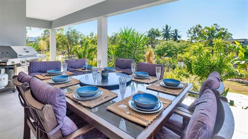 a dining room table with chairs and a table and a table at Tranquillity by the Sea in Hideaway Bay