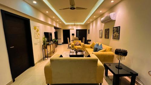 a living room with yellow couches and a ceiling at Montressa Hotel Apartments-Elysium Tower Opposite Centaurus Mall Islamabad in Islamabad