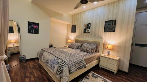 a bedroom with a bed and two night stands with lamps at Montressa Hotel Apartments-Elysium Tower Opposite Centaurus Mall Islamabad in Islamabad