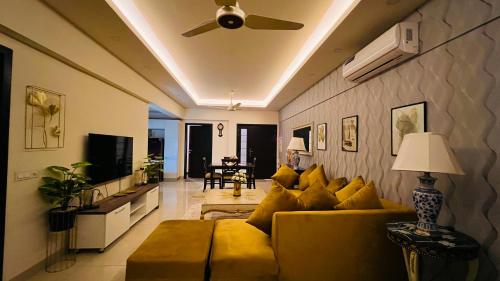 a living room with a yellow couch and a ceiling fan at Montressa Hotel Apartments-Elysium Tower Opposite Centaurus Mall Islamabad in Islamabad