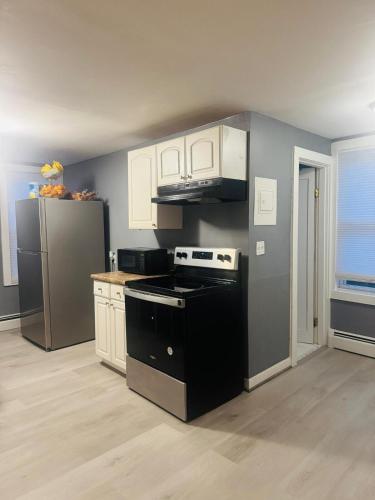 a kitchen with a black and white stove and a refrigerator at 2BR Entire Apt MA Family Home in Haverhill