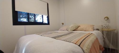 a white bedroom with a bed with a window at Hojas de Otoño SOLO CON SEÑA in Piriápolis