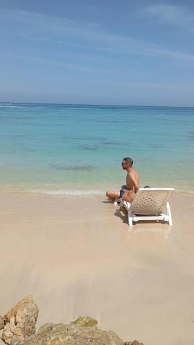 a man sitting in a beach chair on the beach at Atalaya Buceo Cari Blue in Playa Blanca