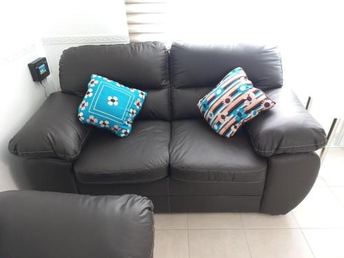a black leather couch with two pillows on it at Casa Residencial en Viñedos, un hermoso espacio in Zempoala
