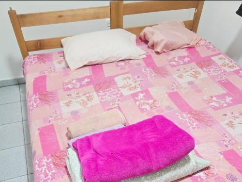 a pink bed with two pillows and towels on it at QUARTO Jd GARCIA in Campinas