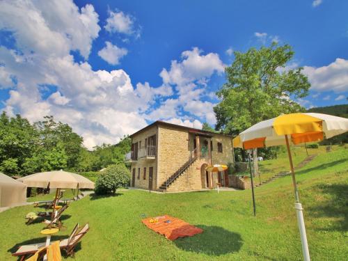 a house with two umbrellas in the grass next to a building at Apartment in Marche with Pool & Terrace in Apecchio