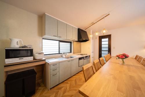 a kitchen with a wooden table and a dining room at アリュール別府 in Beppu